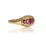 Gold ring with ruby and diamond accents on a white background