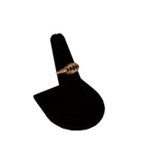 Gold ring with red gemstones on a black ring stand against a white background
