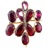 Gold brooch with red gemstones on a white background