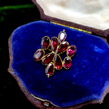 Jewelry box with a brooch featuring red gemstones on a blue cushion