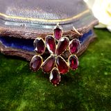 Vintage brooch with red gemstones on a textured green surface