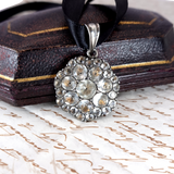 Decorative pendant with rhinestones on a black ribbon, placed on an old document.