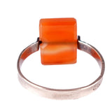 Ring with a square orange gemstone on a white background