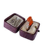 Silver ring with a red stone in an open jewelry box on a white background