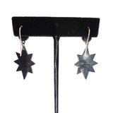 Star-shaped earrings on a black velvet stand against a white background