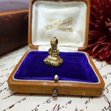 Gold decorative object in a jewelry box with a visible brand name on the lid.