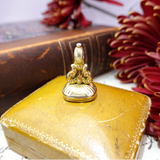 Gold decorative item on a yellow book with red flowers in the background