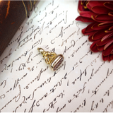 Gold pendant on an old letter with a red flower