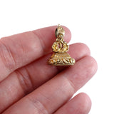 Gold decorative object held between fingers on a white background