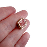 Gold ring with pink stone on a finger against a white background