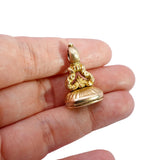 Gold pendant held between fingers on a white background