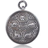 Silver pendant with engraved designs on a white background