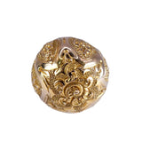 Decorative gold sphere with intricate patterns on a white background