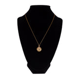 Gold necklace with a pendant on a black mannequin bust against a white background