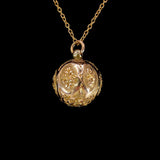 Gold necklace with a round pendant on a black background