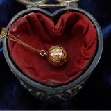 Gold necklace in a heart-shaped jewelry box with red fabric lining