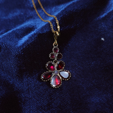 Decorative pendant necklace with red and white stones on a blue velvet background