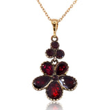 Gold necklace with a red gemstone pendant on a white background