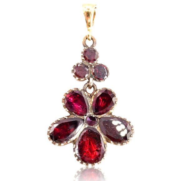 Gold pendant with red gemstones on a white background