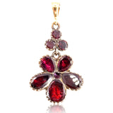 Gold pendant with red gemstones on a white background