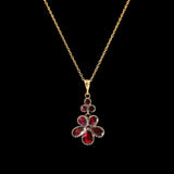 Gold necklace with a red gemstone pendant on a black background