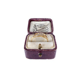 Gold ring in an open jewelry box with a visible brand label on a white background