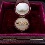 Gold ring in an open jewelry box with a red interior