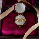 Gold ring with diamonds in an open jewelry box on a red satin lining