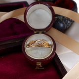 Gold ring with diamonds in an open jewelry box on a red fabric background