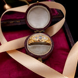 Gold ring with diamonds in an open jewelry box on a red fabric background