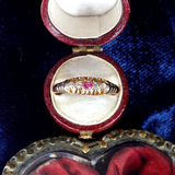 Gold ring with a red gemstone in an open jewelry box on a blue fabric background