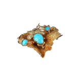 Gold brooch with turquoise stones on a white background