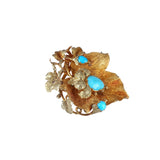 Gold brooch with turquoise stones on a white background
