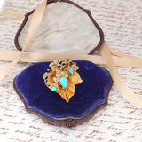 Gold brooch with turquoise stones on a blue velvet cushion, placed on an old letter.