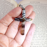 Hand holding a marbled stone pendant against an open book