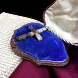 Necklace with a cross pendant on a blue cushion inside an open shell, placed on a book.
