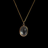 Gold necklace with a black pendant on a black background