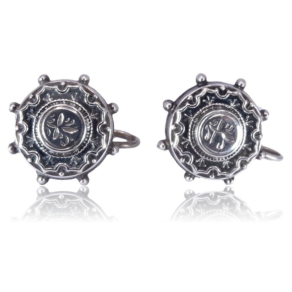 Pair of silver cufflinks with intricate design on a white background