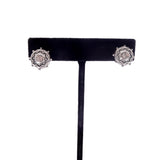 Pair of silver earrings on a black earring stand against a white background