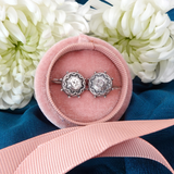 Silver earrings in a pink velvet box with white flowers and a pink ribbon in the background