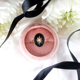 Ring in a pink velvet box with black ribbon and white flowers