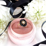 Ring in a pink velvet box with black ribbon on white flowers