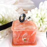 Marbled pink and white jewelry box with a ring on a floral background
