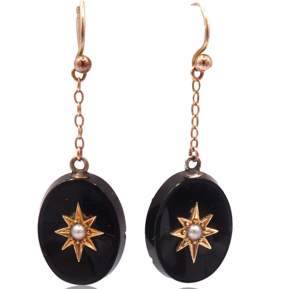 Pair of black oval earrings with gold star designs on a white background