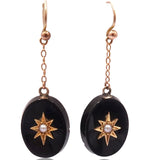 Pair of black oval earrings with gold star designs on a white background