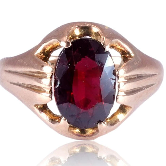 Gold ring with a red gemstone on a white background