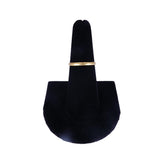 Gold ring on a black velvet ring holder against a white background
