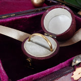 Gold ring in an open jewelry box with a purple interior