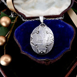 Silver pendant in an open jewelry box with blue lining
