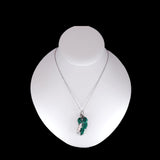 Necklace with a green pendant on a white mannequin bust against a black background